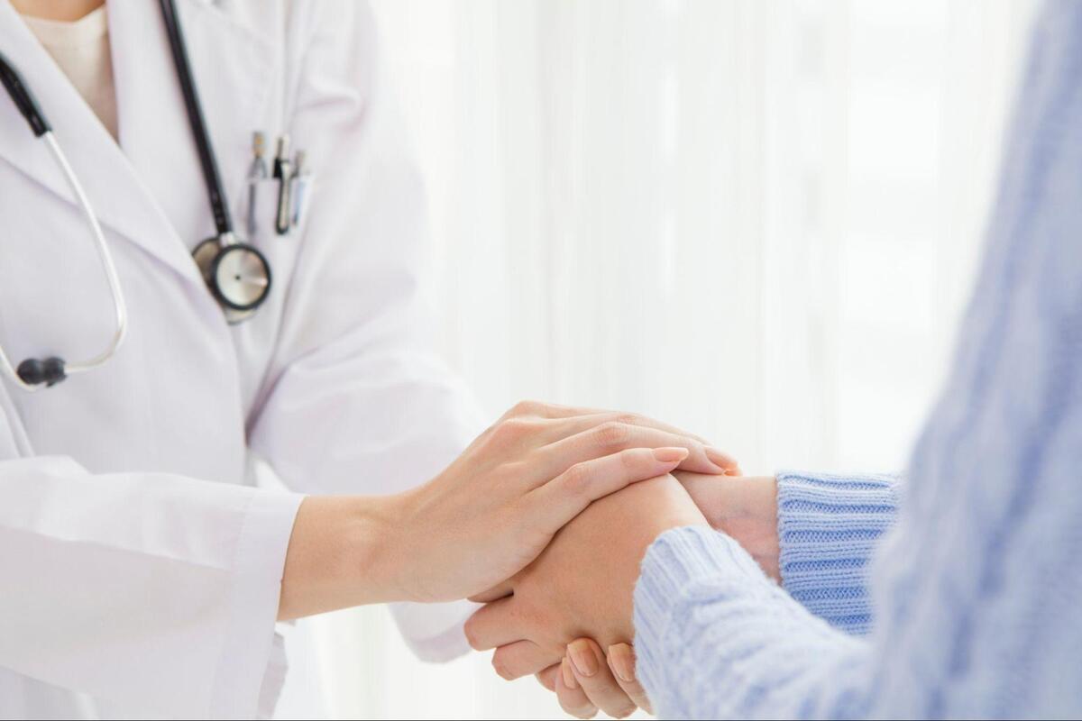 患者の手を握る医者の画像